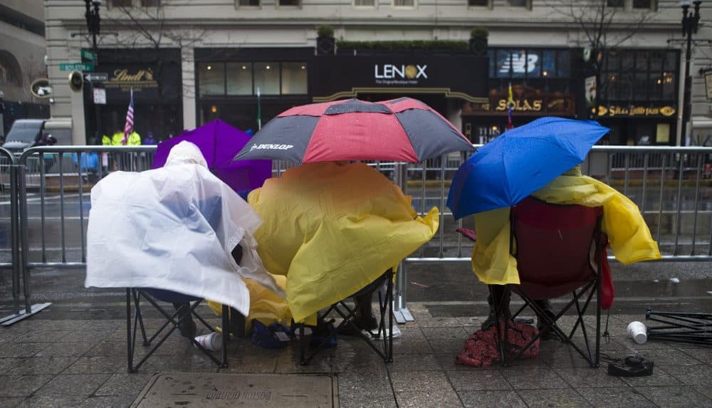 Spectators camp out in the wind and rain along Boylston Street. (Jesse Costa/WBUR))