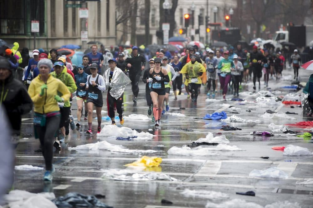 Marathoners run up a plastic poncho-littered Hereford Street not far from the finish line. (Jesse Costa/WBUR)