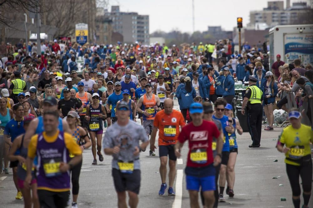 Runners pour over the Mass Pike Bridge at the Mile 25 marker welcoming them to Boston. (Jesse Costa/WBUR)