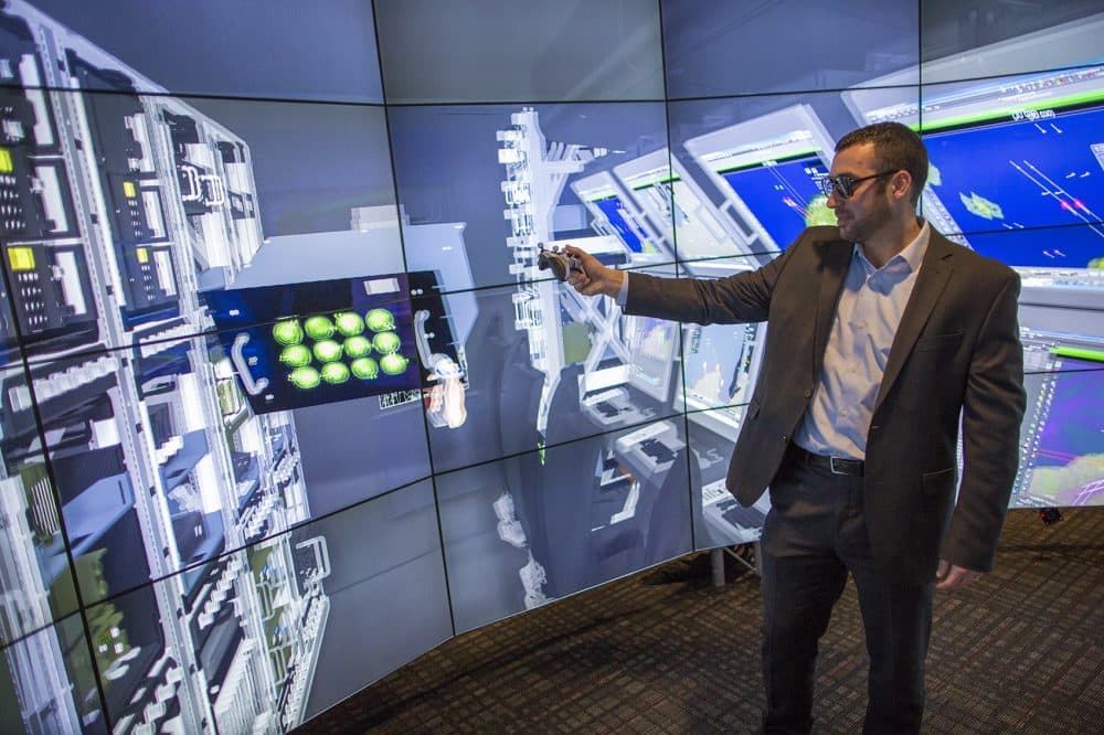 Dan Gale, manager of the Immersive Design Center, demonstrates the interactive features of Raytheon's Customer Automatic Virtual Environment (CAVE). (Jesse Costa/WBUR)