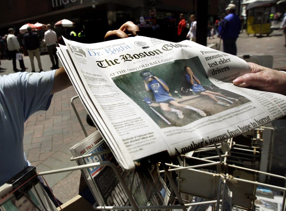A customer buys a Boston Globe newspaper from a street newsstand in Boston's Downtown Crossing in 2009. (Elise Amendola/AP)