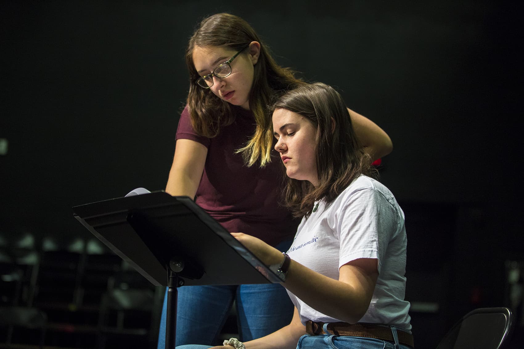 Gann Academy senior Nessa Goldhirsch Brown looks over junior Julia Clardy's shoulder to review a section of "Natural Shocks." (Jesse Costa/WBUR)