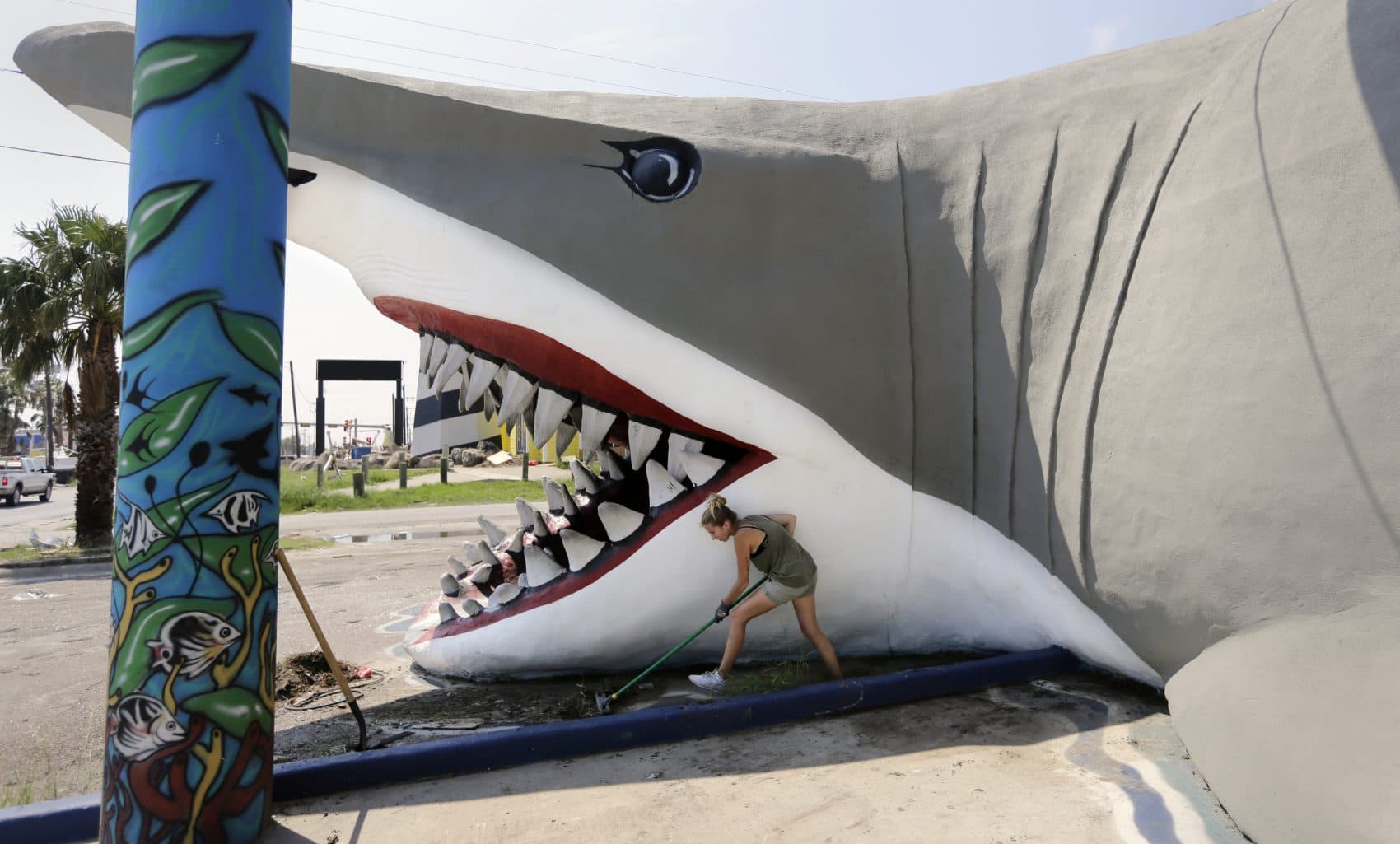 In this Friday, Sept. 29, 2017 photo, Olya Soya works to clear debris from the beach shop, Destinations, in Port Aransas, Texas. The storm damaged or destroyed 80 percent of local homes and businesses and arrived just before Labor Day, wiping out the lucrative summer season's final weeks. (Eric Gay/AP)