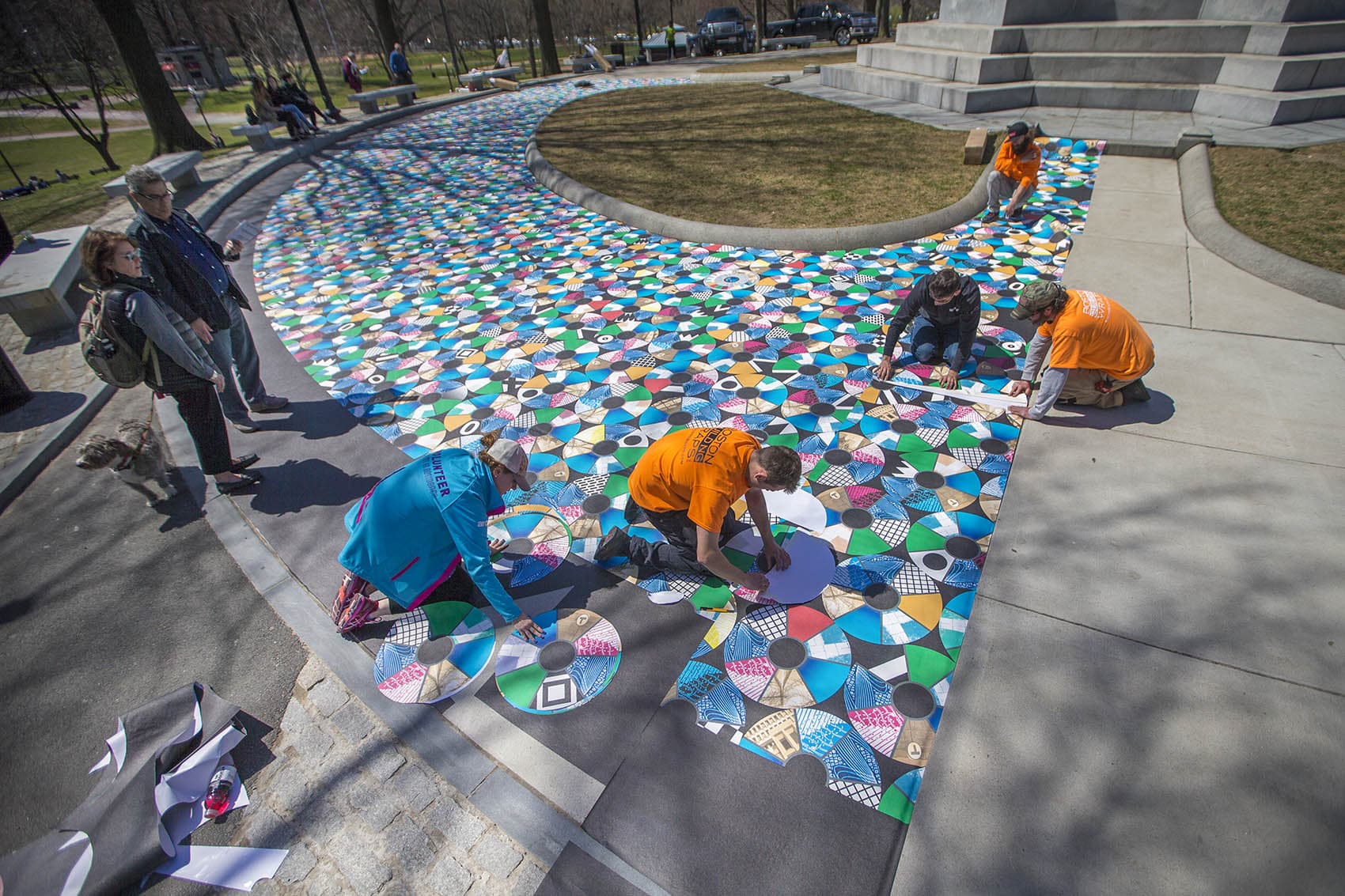 Julia Vogl, in blue, works with a team from Boston Building Wraps to install the &quot;Pathways to Freedom&quot; project around the Soldiers and Sailors Monument on Boston Common. (Jesse Costa/WBUR)