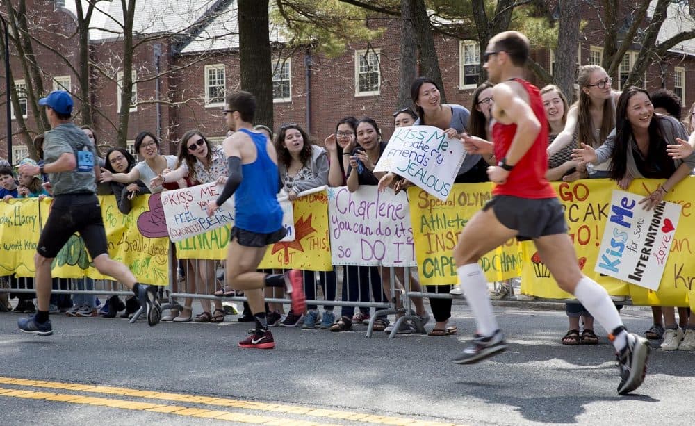 Following a Marathon tradition, Wellesley students hold out "Kiss Me" signs, to runners as they pass through the "scream tunnel." (Robin Lubbock/WBUR)