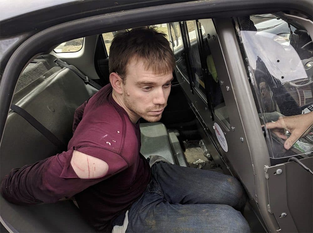 In this photo released by the Metro Nashville Police Department, Travis Reinking sits in a police car after being arrested in Nashville, Tenn., on Monday, April 23, 2018. Police said Reinking opened fire at a Waffle House early Sunday, killing at least four people. (Metro Nashville Police Department via AP)