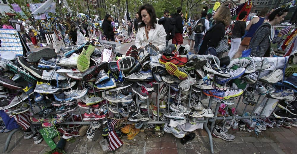 Denise White, of Duxbury, pauses to read notes written on running shoes at the site of a memorial near the finish line of the Boston Marathon. (Charles Krupa/AP)
