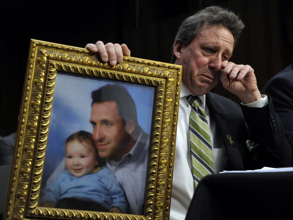 Neil Heslin, the father of a 6-year-old boy who was slain in the Sandy Hook massacre in Newtown, Conn., holds a picture of himself with his son Jesse and wipes his eye while testifying on Capitol Hill in Washington, Wednesday, Feb. 27, 2013. (Susan Walsh/AP)