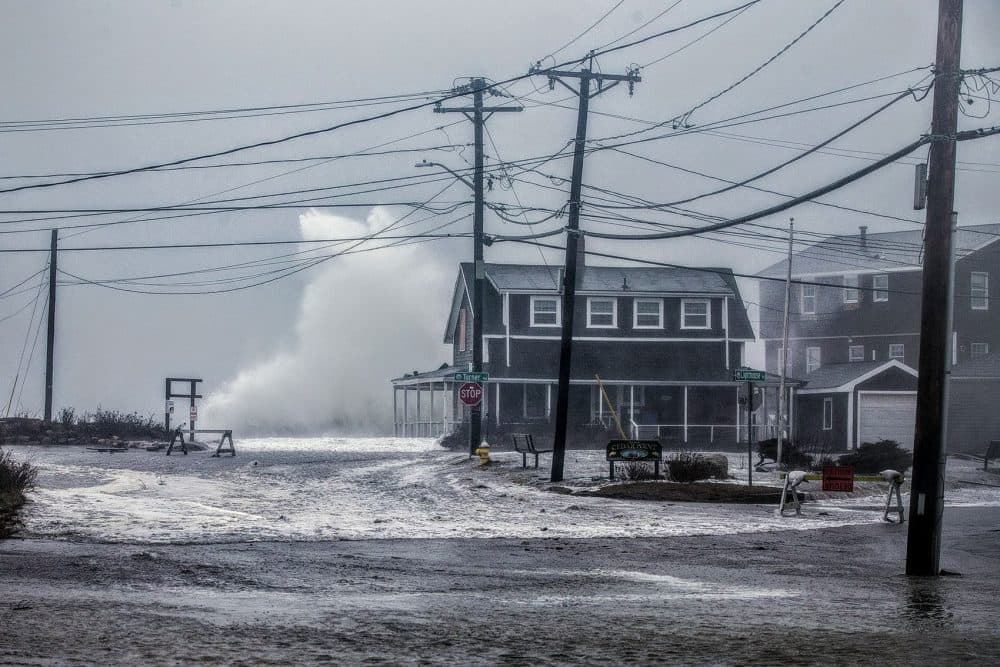 A wave crashes high above a house in Scituate during a nor'easter in 2018. (Jesse Costa/WBUR)