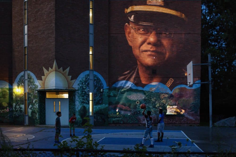An image of Boston Police Captain Haseeb Hosein projected on the Lee School in the B-3 neighborhood where he works. (Courtesy Erik Jacobs)