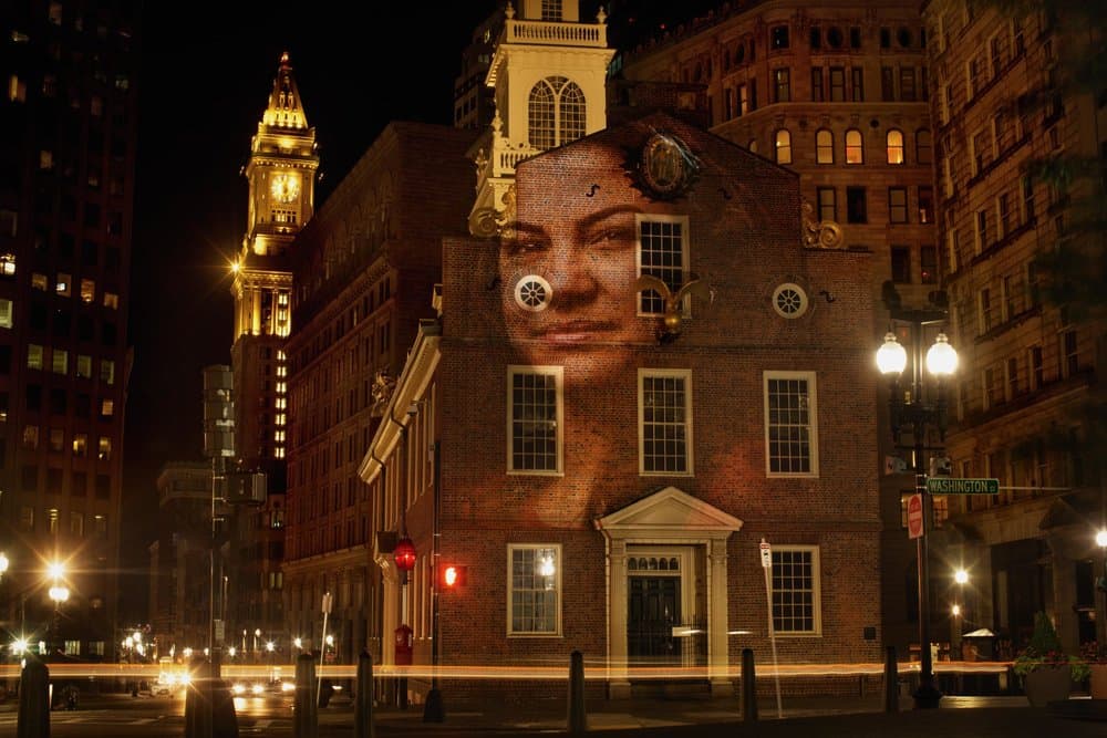 A portrait of Jennis Perez, who is from Cuba, projected on the Old State House in Boston. (Courtesy Erik Jacobs)