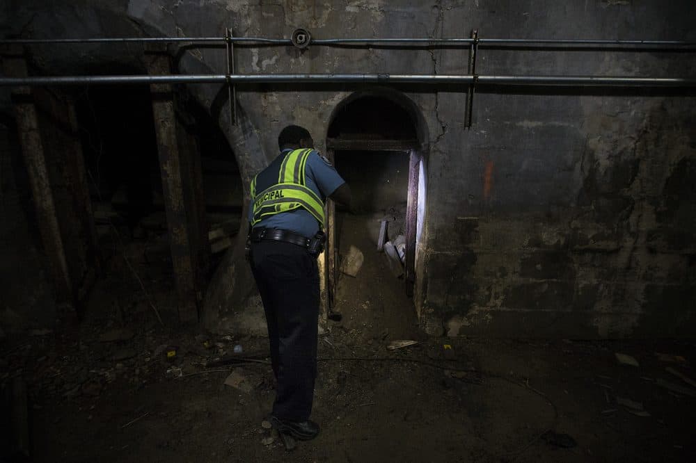 Marc Voltus shines his flashlight into an opening in the side of the tunnel. (Jesse Costa/WBUR)