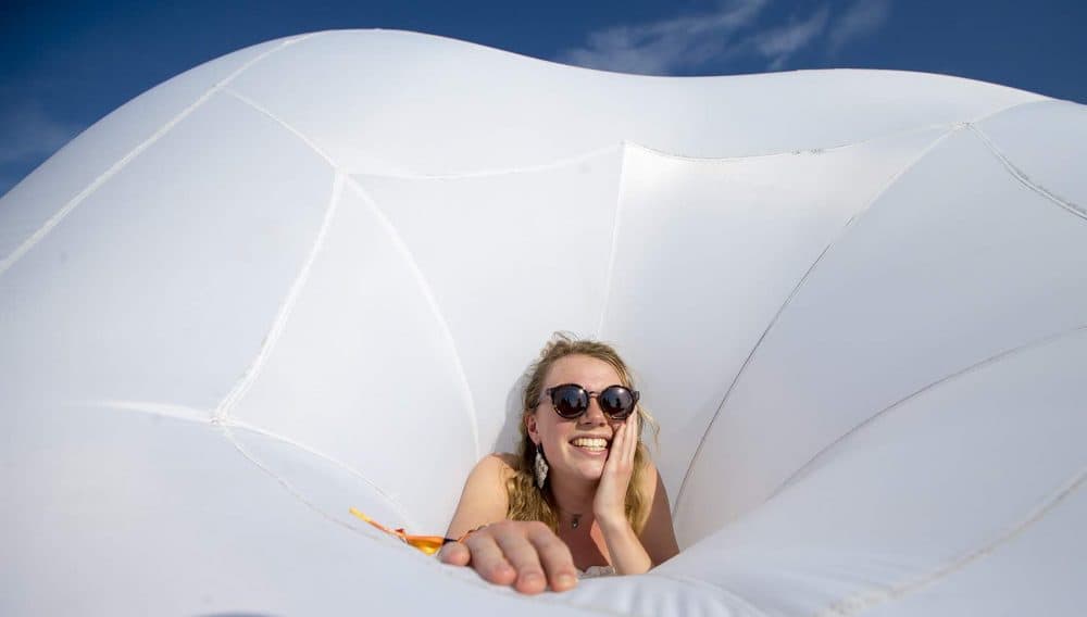 Kate Lietz sticks her head through the hole of an inflatable sculpture at Boston Calling. (Jesse Costa/WBUR)