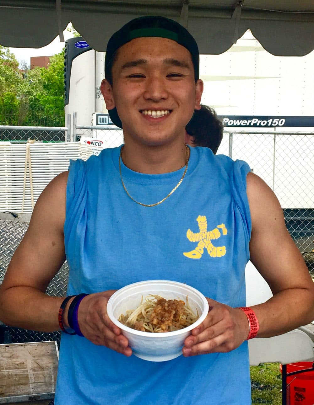 Kansei Yasuda holds a bowl of ramen in a to-go container at Boston Calling He works at Yume Wo Katare in Porter Square. (Andrea Shea/WBUR)