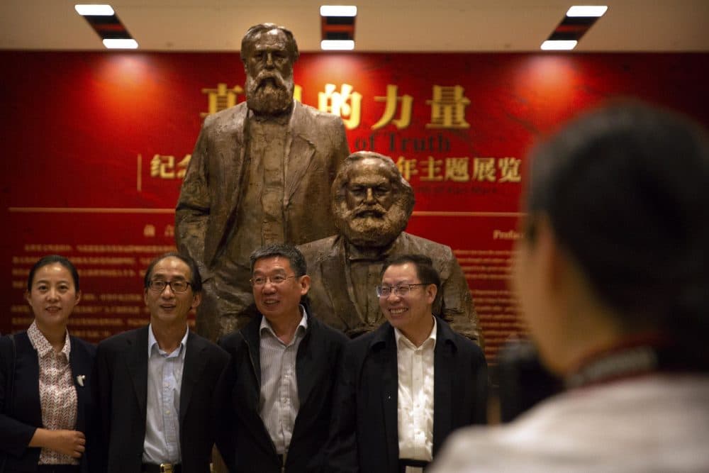 Visitors line up for a group photo in front of a sculpture of Karl Marx and Friedrich Engels at an exhibition to commemorate the 200th anniversary of the birth of Marx at the National Museum in Beijing, Saturday, May 5, 2018. (Mark Schiefelbein/AP)