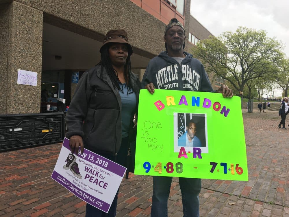 Federico and Monica Haney Brown hold a sign with a picture of their late son, Brandon. (Simon Rios/WBUR)