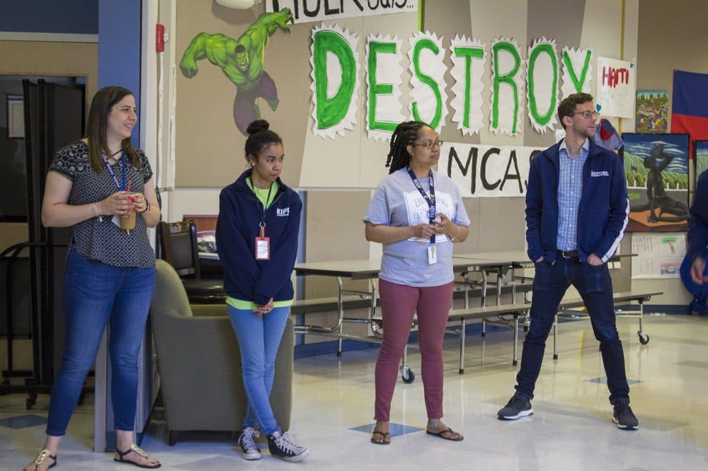 In front of a &quot;Destroy MCAS&quot; sign on the wall, from left, Megan Sanchez, Samantha Suarez, Pertreena Cherrie and Peter Perry-Friedman pause for a morning staff meeting at KIPP Academy Boston. (Carrie Jung/WBUR)