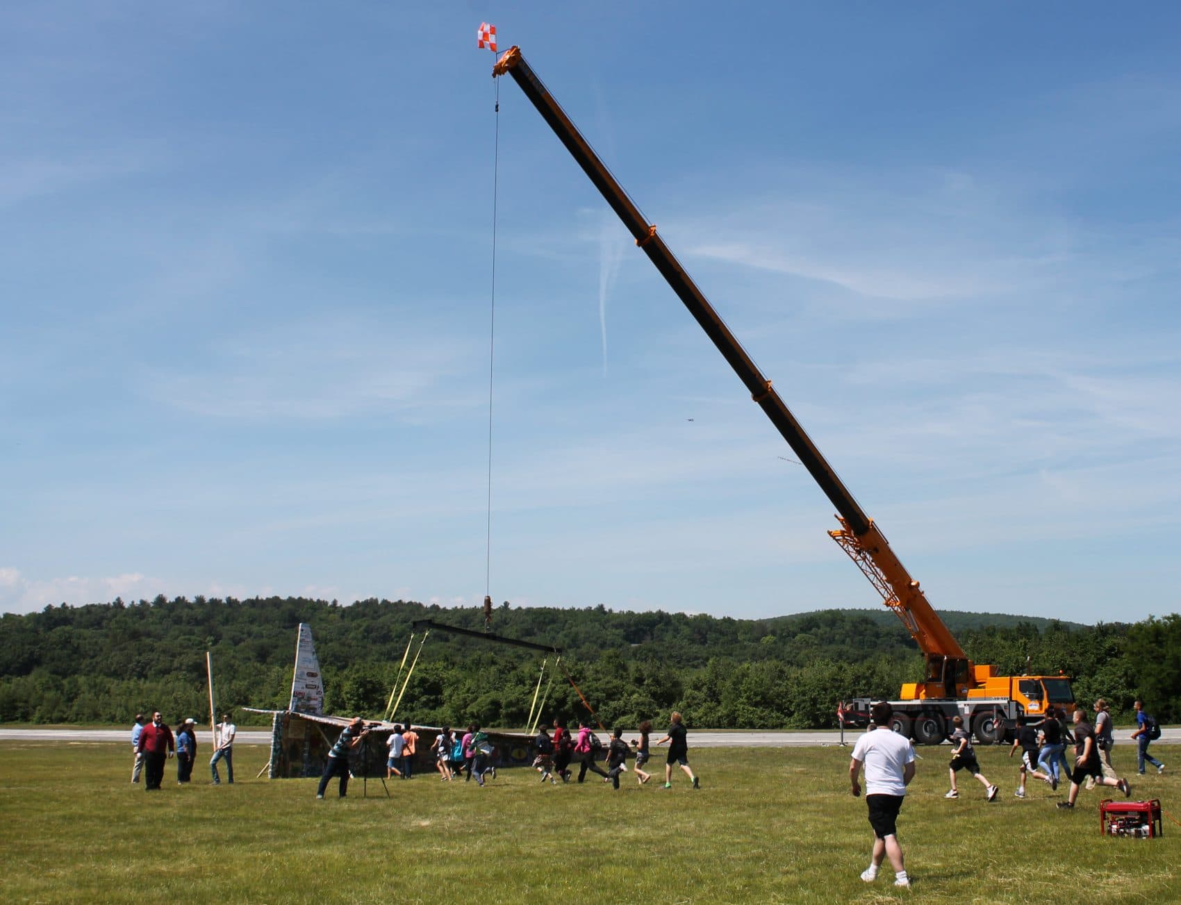 Students and locals run to get a closer look at the paper airplane at the unveiling on Tuesday. (Amy Gorel/WBUR)