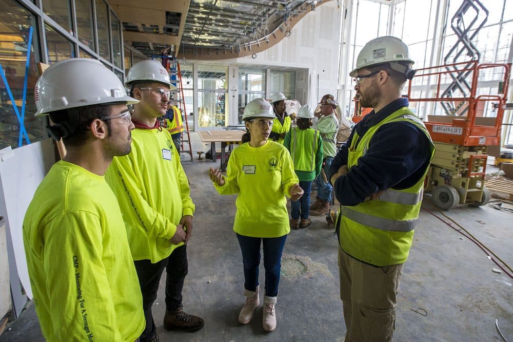 Lillia Sakher, center, asks Walsh Brothers assistant superintendent and mentor Aidan Buick some questions regarding the Klarman Hall construction project at Harvard Business School, as Djilali Chaker, left, and Ardi Elshani listen in. (Jesse Costa/WBUR)