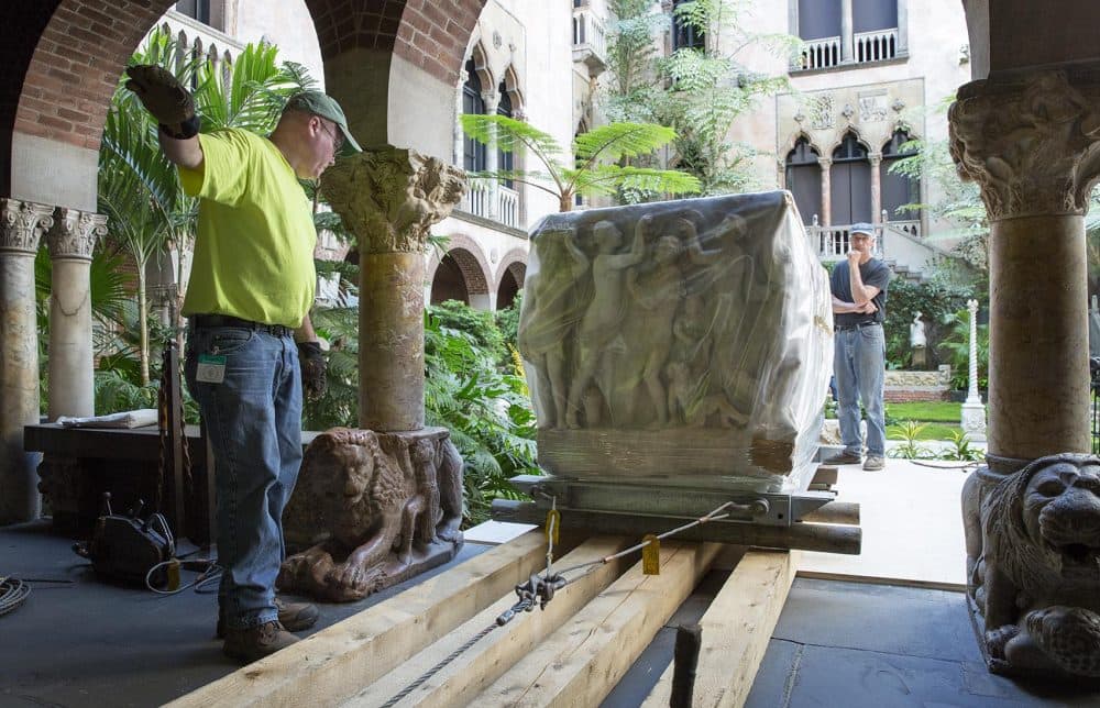 The rigging crew rolls the sarcophagus wrapped in plastic along planks through the museum. (Robin Lubbock/WBUR)