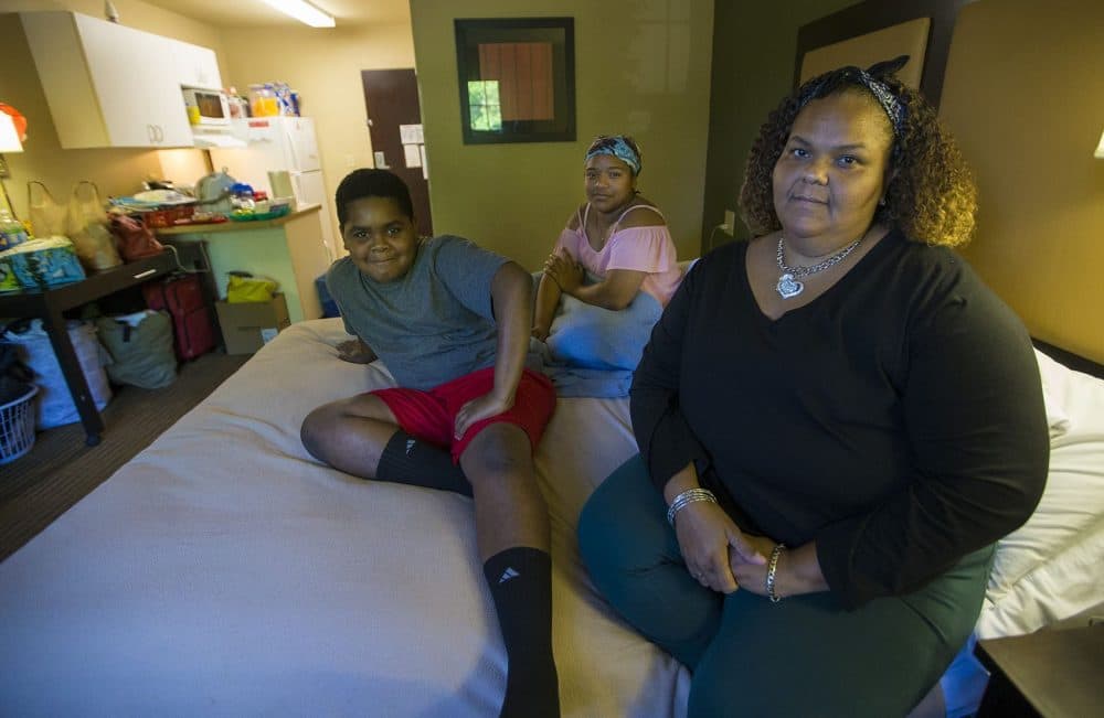 Lisbeth Sandoval, (far right), her daughter, Sheylibeth, and her son, Stephen, inside a hotel room in Lowell. (Jesse Costa/WBUR)