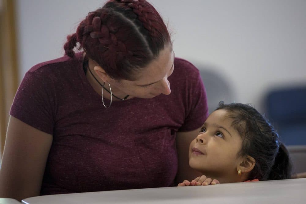 Genie Garda, and her 4-year-old daughter, Getzaynoe Hernandez, sit at a table at a potluck dinner in Dracut for women who evacuated from Puerto Rico. (Jesse Costa/WBUR)