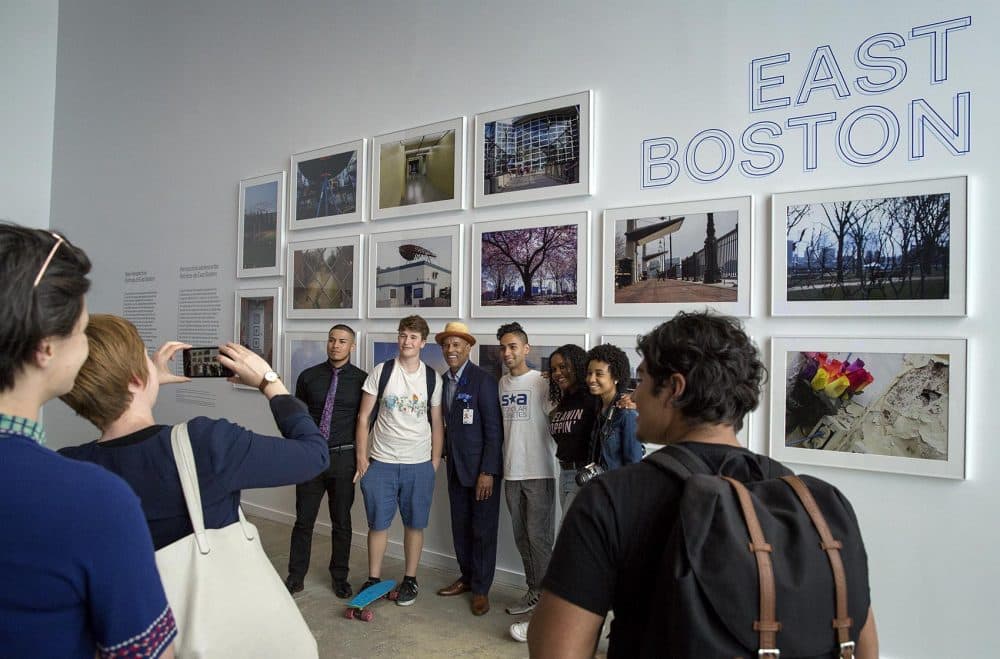 Visitors to the inaugural exhibition of the ICA Watershed pose for a photo in front of a wall of photographs of East Boston by teens from the ICA's digital photography program. (Robin Lubbock/WBUR)
