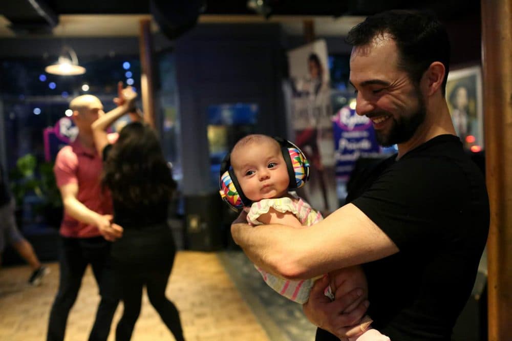 Mat Gauvin holds his daughter, Mia, who wears noise-cancelling headphones, during a recent Salsa Sundays at Ryles Jazz Club in Cambridge. (Hadley Green for WBUR)