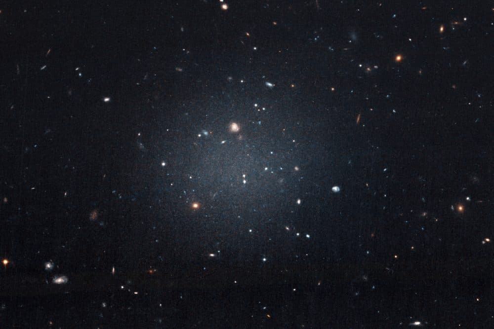 This Nov. 16, 2017 image made with the Hubble Space Telescope shows the diffuse galaxy NGC 1052-DF2, lighter area in center. Several other galaxies can be seen through it. The unusual galaxy’s stars are speeding around with no apparent influence from dark matter, according to a study published on Wednesday, March 28, 2018 in the journal Nature. (P van Dokkum/NASA/ESA via AP)