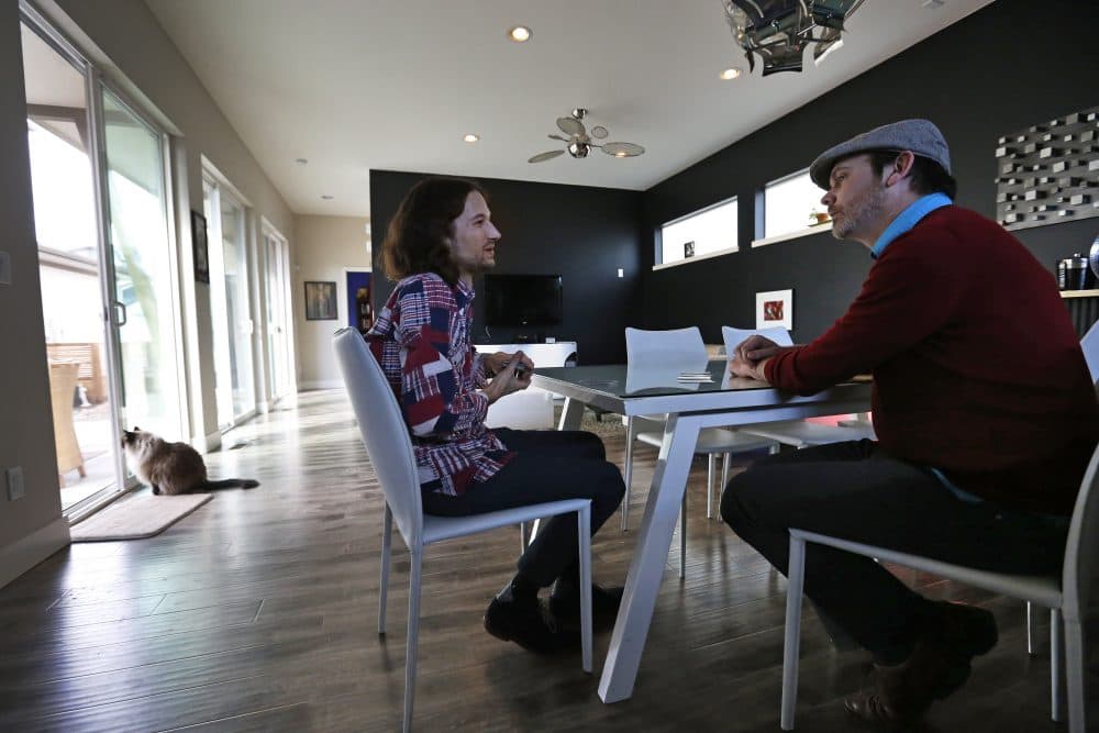 In this March 13, 2014 photo, Dave Mullins, left, and his husband Charlie Craig play cards and talk after a work day, at their home in Westminster, Colo. The couple filed a legal complaint with the Colorado Civil Rights Commission against a Denver-area baker who refused to make a wedding cake for the two men, based on his religious beliefs. (Brennan Linsley/AP)