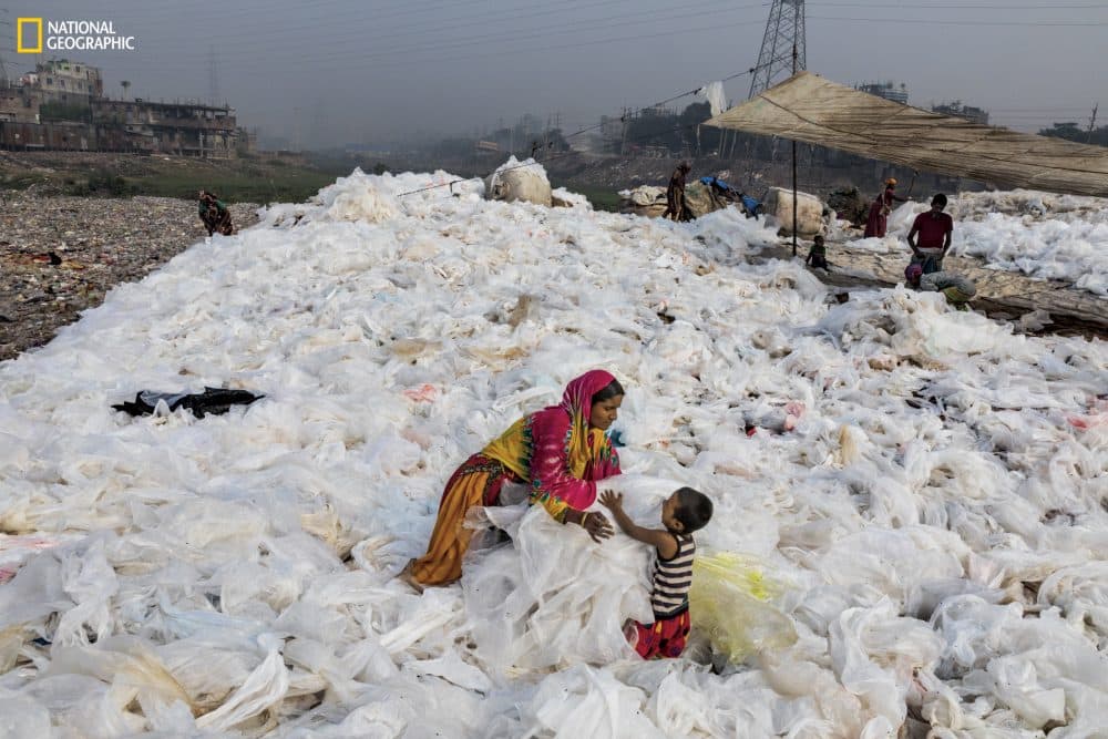 After sheets of clear plastic trash have been washed in the Buriganga River, in Dhaka, Bangladesh, a woman spreads them out to dry,turning them regularly—while also tending to her son. The plastic will eventually be sold to a recycler. Less than a fifth of all plastic gets recycled globally. In the U.S. it’s less than 10 percent. (Courtesy Randy Olson/National Geographic)