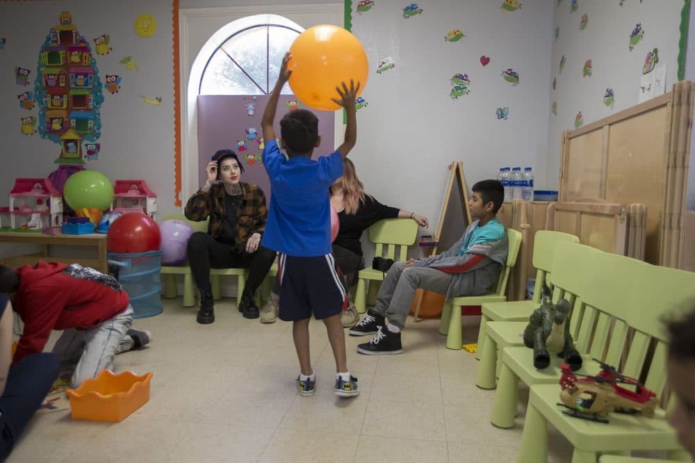 A young boy plays with a ball with volunteers at Catholic Charities in McAllen, Texas. (Jesse Costa/WBUR)