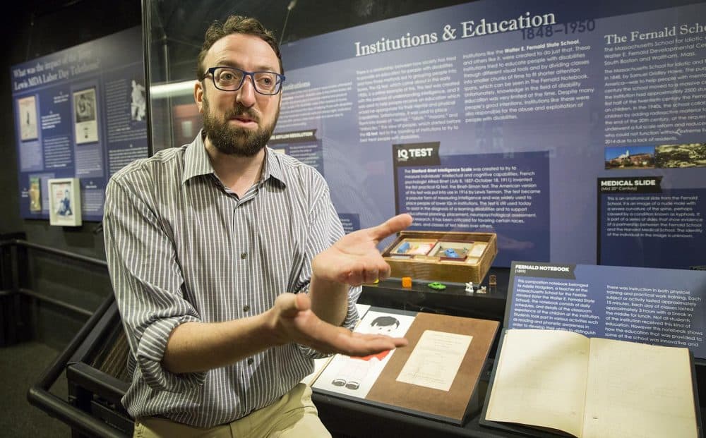 Gann Academy history teacher Alex Green talks with students at the &quot;Disability History of the United States&quot; exhibit. (Robin Lubbock/WBUR)