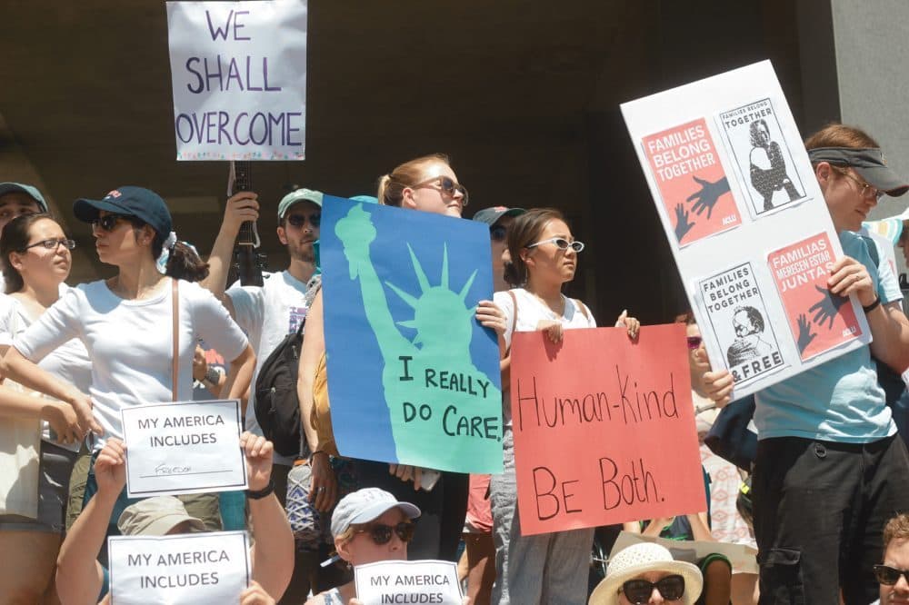 Protesters hold signs at an immigration rally in Boston in 2018. (Quincy Walters/WBUR)
