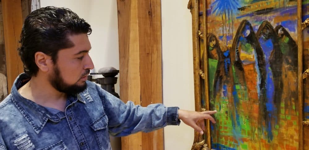 Iraqi Ahmed Alkarkhi points out the colors he began painting with since moving to the U.S. (Carmel Delshad/WAMU)