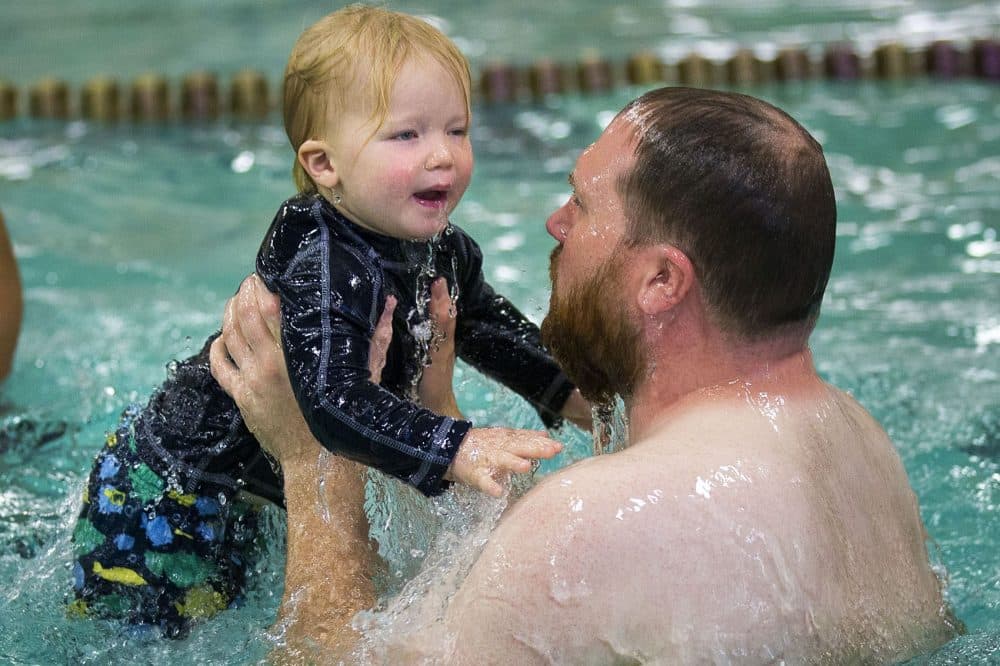 Twenty-three-month-old Ferdinand Smith and his father Nate come up from the water after dunking themselves during a game of Ring Around the Rosie during a toddler swimming lesson at the YMCA in Waltham. (Jesse Costa/WBUR)