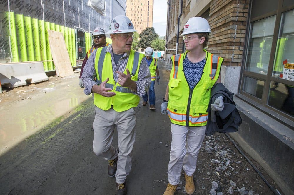Project manager Mike Harris walks with Wentworth rising junior Shannon Sturz through what will become Wentworth's new building for engineering, innovations and sciences. (Jesse Costa/WBUR)