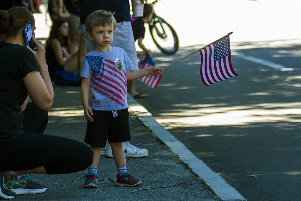 A young boy wearing a police badge sticker stands near the church where Officer Michael Chesna's funeral was held Friday. (Jesse Costa/WBUR)