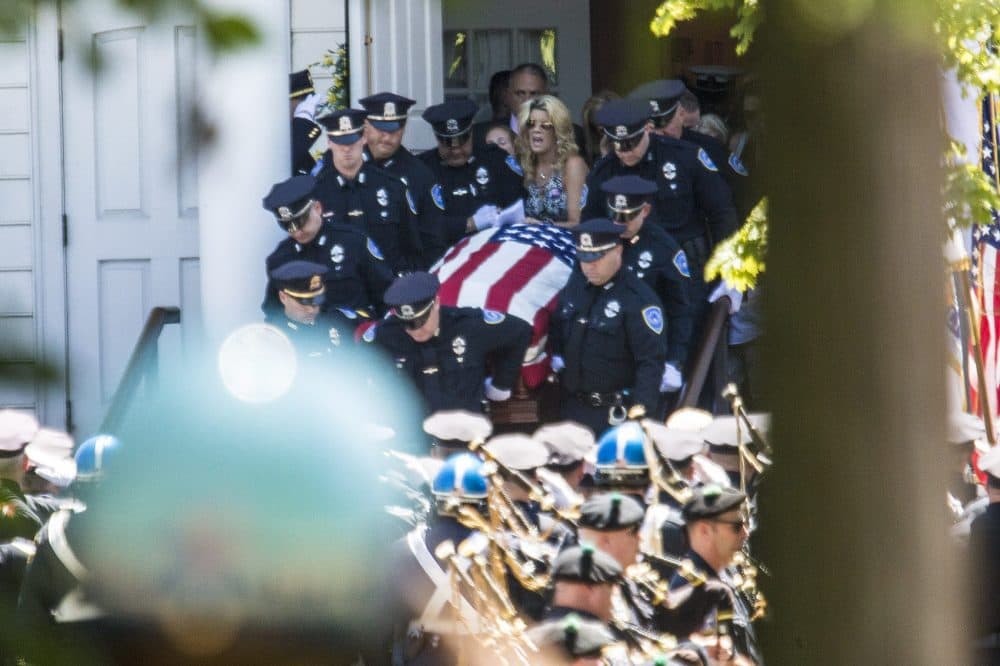An emotional and grieving Cindy Chesna follows the casket of her slain husband. Sgt. Michael Chesna, as it is brought out of the church. (Jesse Costa/WBUR)