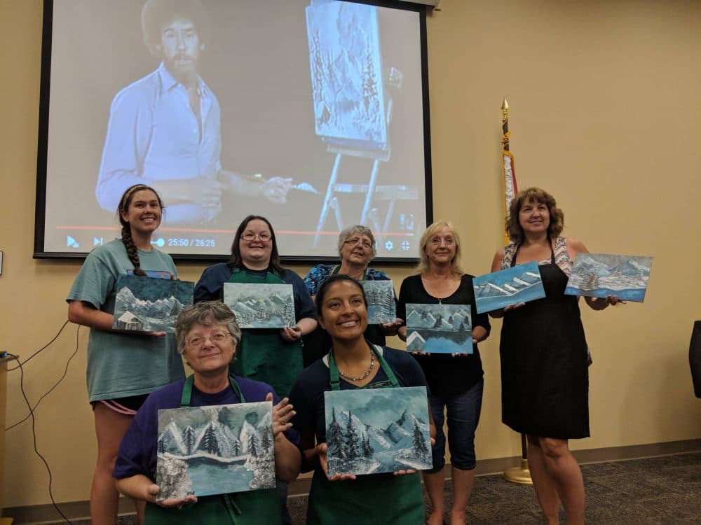 Participants pose with their completed Bob Ross paintings. (Courtesy Sarah Burris)