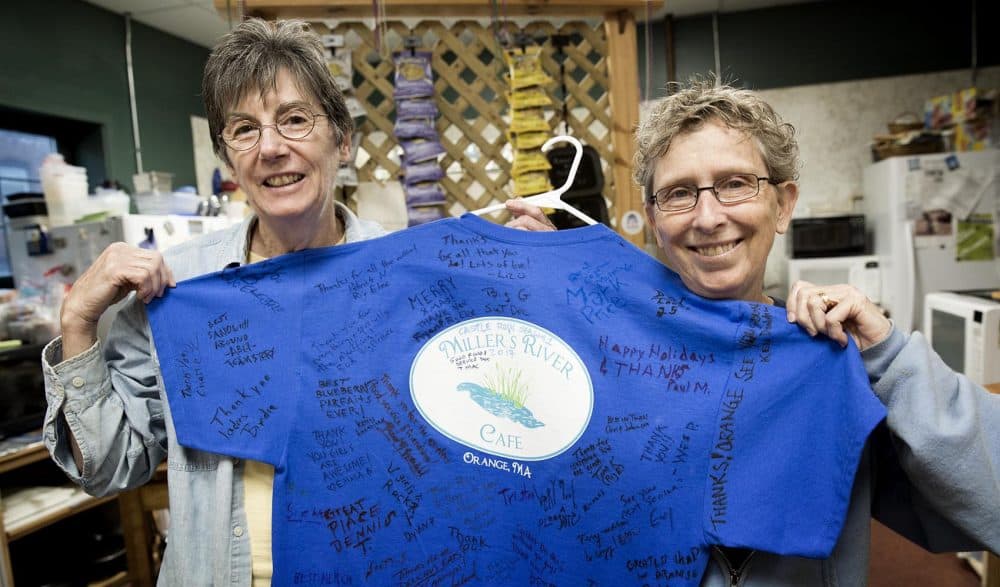 Kris Burns and Jeanie Miller hold up a T-shirt signed by members of the &quot;Castle Rock&quot; crew who visited their cafe in Orange during filming. (Robin Lubbock/WBUR)