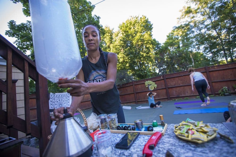 Kijana Rose fills a plastic balloon with marijuana vapor for one of her Beginners Ganja Yoga Flow students. (Jesse Costa/WBUR)