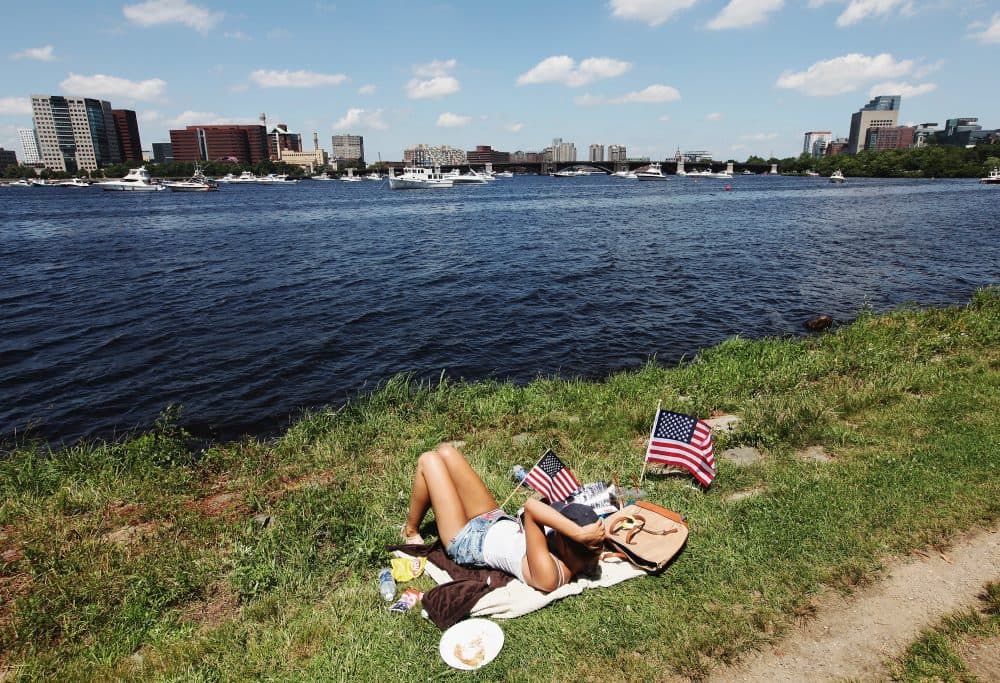A woman sits with American flags during July Fourth festivities on the Esplanade in Boston in 2013. (Mario Tama/Getty Images)