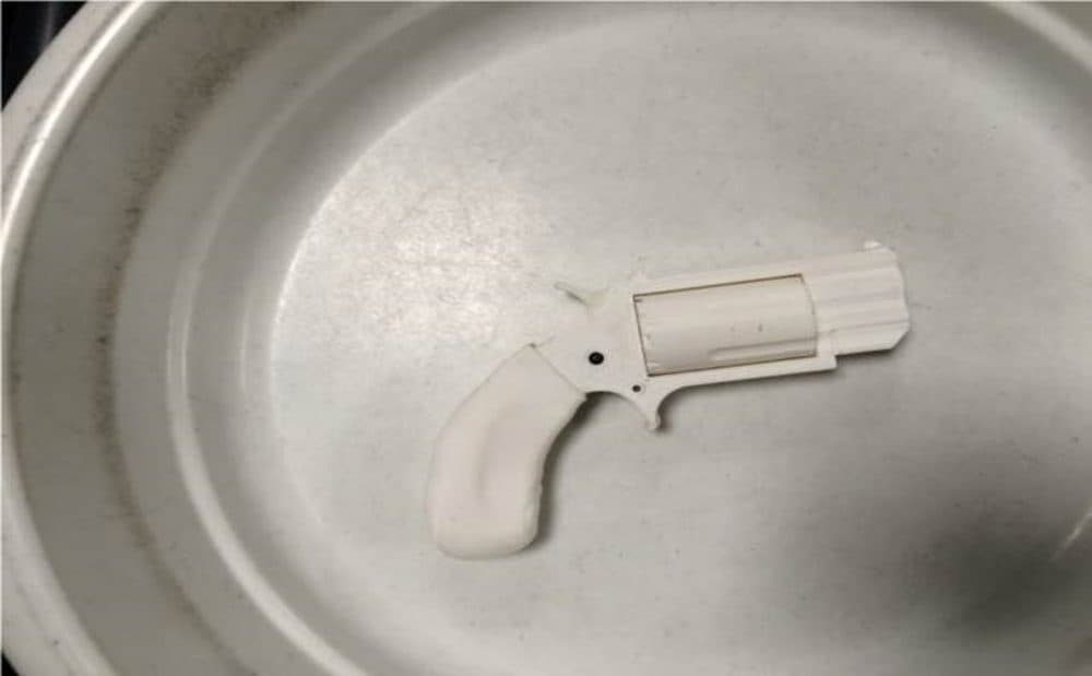 This Aug. 4, 2016, photo, provided by the Transportation Security Administration shows the plastic replica revolver TSA agents recovered from a passenger's carry-on bag at Reno-Tahoe International Airport in a bowl used at the security checkpoint in Reno, Nev. The man agreed to leave the prohibited, fake firearm made from a 3D printer behind and was allowed to board the plane without incident. (Transportation Security Administration via AP)