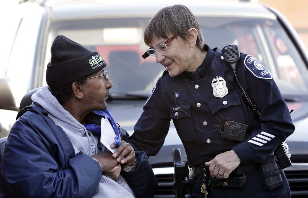 In this March 12, 2015, file photo, Seattle police officer Debra Pelich, right, wears a video camera on her eyeglasses as she talks with Alex Legesse before a small community gathering in Seattle. While the Seattle Police Department bars officers from using real-time facial recognition in body camera video, privacy activists are concerned that a proliferation of the technology could turn the cameras into tools of mass surveillance. The ACLU and other organizations on Tuesday, May 22, 2018, asked Amazon to stop selling its facial-recognition tool, called Rekognition, to law enforcement agencies. (Elaine Thompson/AP)