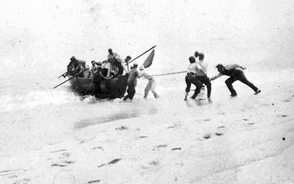 In this 1918 file photo provided by the Orleans Historical Society, people help survivors arriving on a lifeboat on the shore after a German submarine attack on Orleans on July 21, 1918. Orleans was the only town on U.S. soil to receive enemy gunfire during World War I. (Courtesy of Orleans Historical Society via AP)
