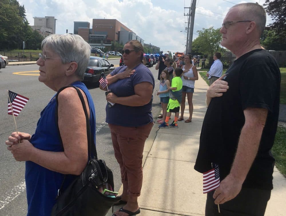 People pay their respects to Officer Michael Chesna, as a procession carrying his body goes through Weymouth Monday. Chesna and Vera Adams were killed Sunday morning. (Yasmin Amer/WBUR)