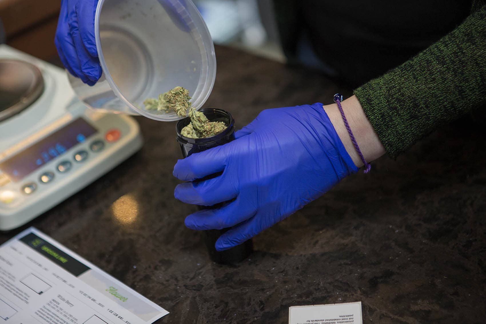Patient Service Associate Ashley Cabana dispenses 14 grams (1/2 oz) of Facewreck marijuana flower for patient Sam Brown. (Jesse Costa/WBUR)