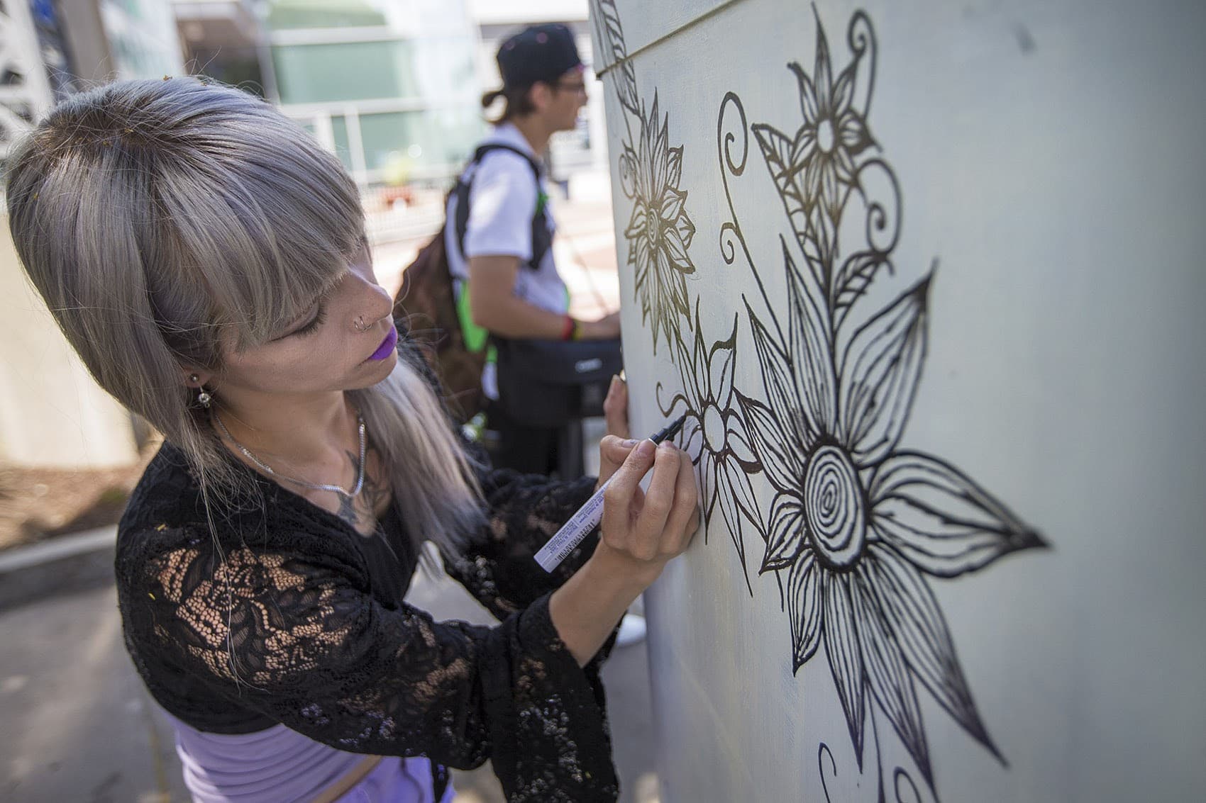 Artist Kitty Zen drawing a design on an electrical box on the corner of Massachusetts Ave and Melnea Cass Boulevard, July 2017. (Jesse Costa/WBUR)