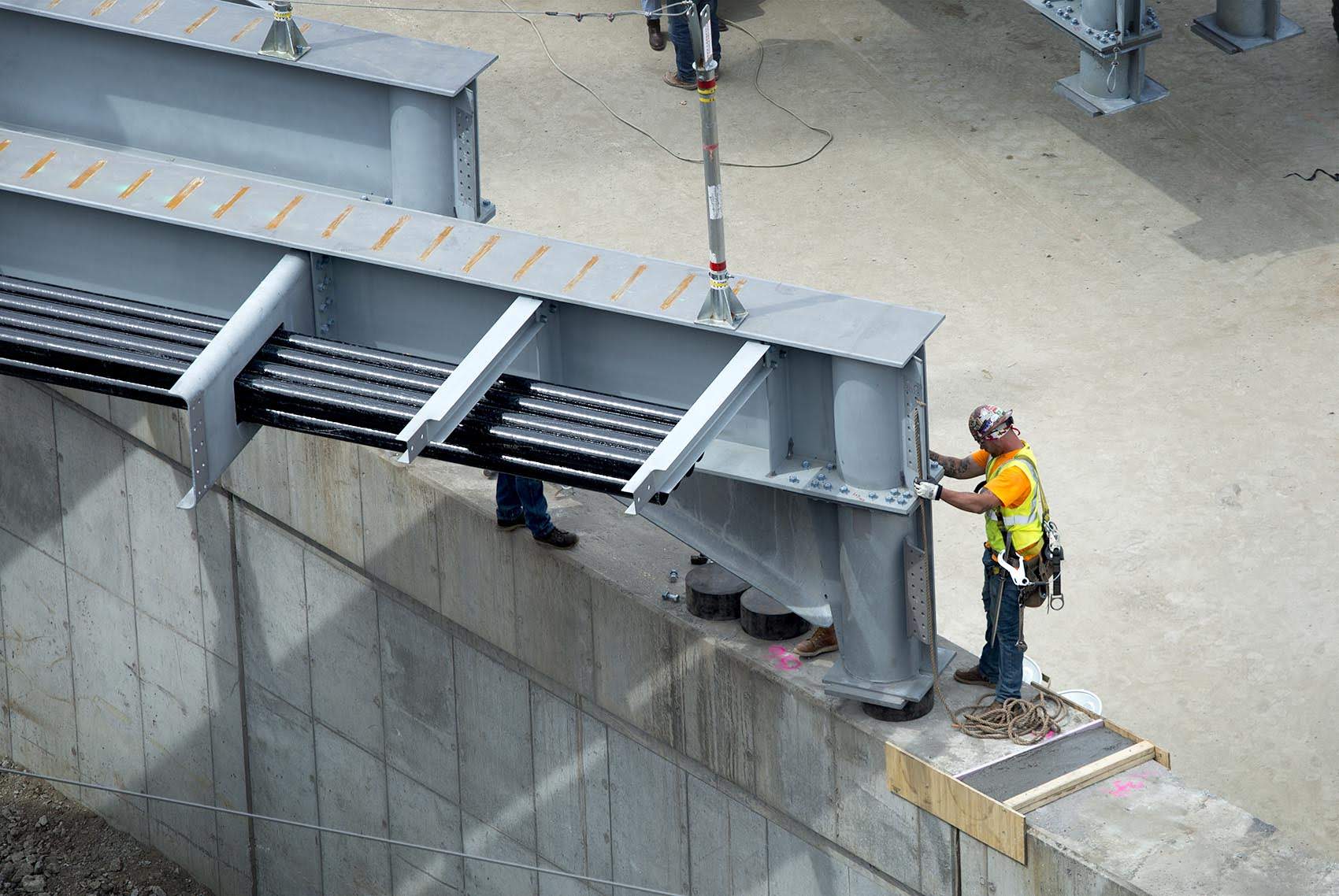 A construction worker eases a huge new steel beam into position as part of construction to replace the westbound side of the Commonwealth Avenue Bridge. (Robin Lubbock/WBUR)